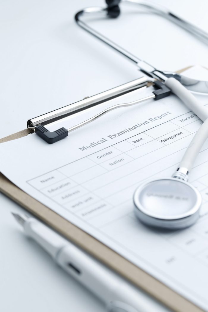 Medical examination report and stethoscope on white desktop