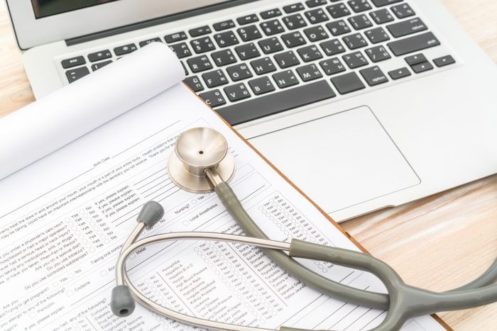 Stethoscope and prescription on laptop.
