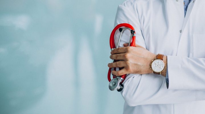 Young handsome physician in a medical robe with stethoscope
